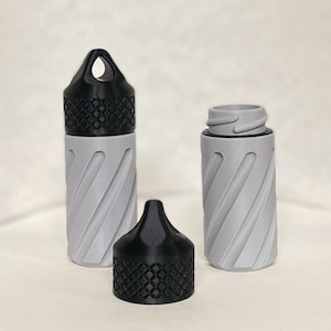 May include: Two gray and black twist-top containers with a textured design. The containers are made of plastic and have a black lid with a small loop on top.