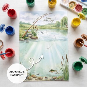 May include: Watercolor painting with a fishing theme, featuring a lake scene with a fishing rod and the text "I CAUGHT THE BEST DAD EVER! Happy Father's Day!". Includes an area to add a child's handprint, surrounded by paint pots.