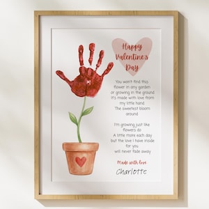 May include: Framed Valentine's Day art print featuring a handprint flower in a terracotta pot with a heart. The print includes the text "Happy Valentine's Day" and a poem, signed "Made with love Charlotte."