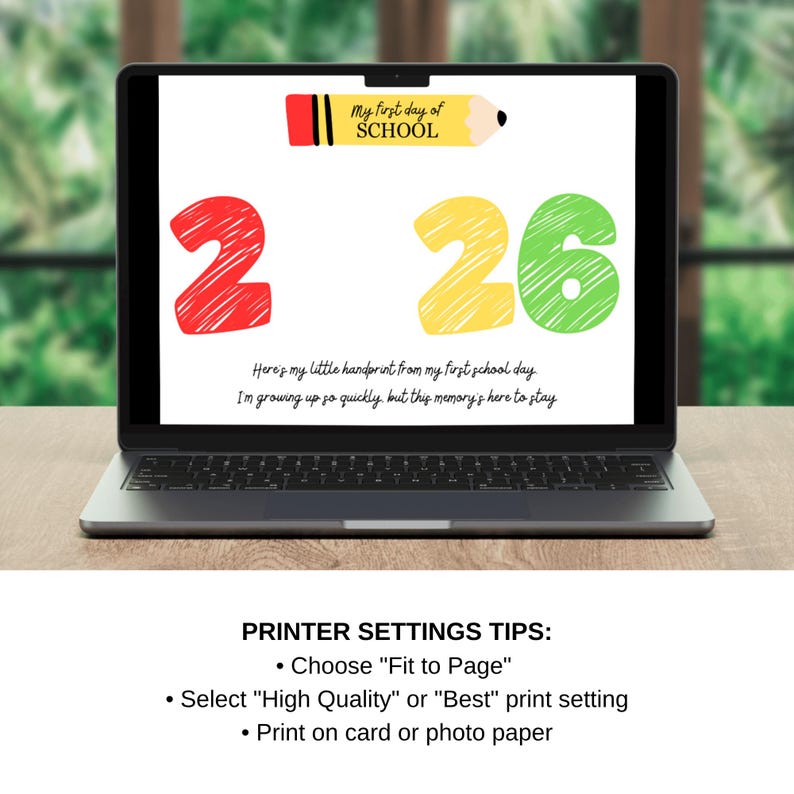 May include: A laptop displays a colorful print for a child's first day of school. The design includes a red '2', a yellow '26', and a pencil graphic with the text 'My first day of SCHOOL'. Below, text reads, 'Here's my little handprint...'.