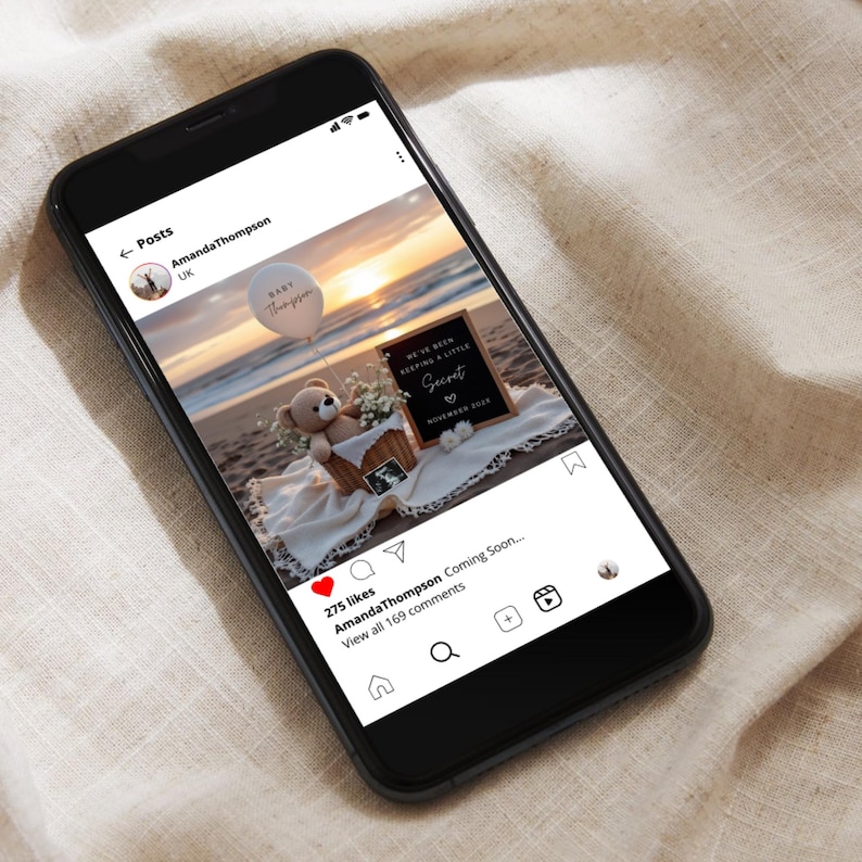 May include: A smartphone displays a beach scene with a baby announcement. A teddy bear, flowers, and a sign that reads "We've been keeping a little secret" are in a basket. A balloon says "Baby Thompson".