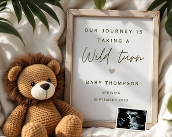 Peut inclure: Une annonce encadrée avec le texte "Our journey is taking a wild turn" et "Baby Thompson arriving September 202X". Un jouet en crochet en forme de lion est placé devant le cadre. Une image d'échographie se trouve dans le coin inférieur droit du cadre.
