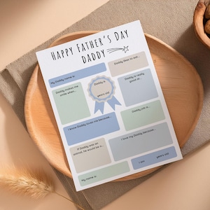 Op de afbeelding: Een printbare Vaderdagkaart met invulvelden voor kinderen om over hun vader te schrijven. De kaart heeft een blauw en wit kleurenschema met een ster en een lint. De tekst op de kaart luidt "Gelukkige Vaderdag Pap".