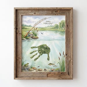 May include: Framed watercolor art print with a fishing theme. The artwork features a handprint transformed into a fish, with a fishing rod and the text "I caught the best Dad ever! Happy Father's Day!" in the background. The frame is made of rustic wood.
