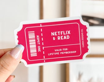 Può includere: Un adesivo rosa e bianco con il testo "Netflix & Read" e "Valido per l'abbonamento a vita". L'adesivo ha la forma di un biglietto e ha le parole "Admit One" stampate su di esso.