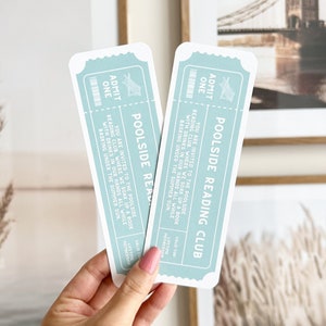 May include: Two blue and white tickets with the text "Poolside Reading Club" and "You are invited to the poolside reading club, where we soak up a book with drinks in our hands all while basking under the summer sun."