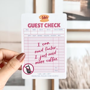 Op de afbeelding: Een witte gastbon met roze rasterlijnen en tekst. Bovenaan staat "Luke's GUEST CHECK". De bon heeft de tekst "I can read faster, I just need more coffee." Er is een symbool voor geen telefoon aanwezig. Onderaan staat "coffee, coffee, coffee".