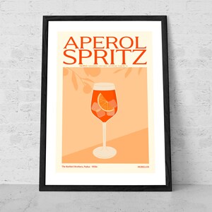 May include: A vintage-style poster featuring an illustration of an Aperol Spritz cocktail in a tall glass with an orange slice and ice cubes. The poster is on a peach background with a black frame and the text "APEROL SPRITZ" in bold, orange letters. The text "The Barbieri Brothers, Padua - 1950s" and "MURILLOS" are also included.