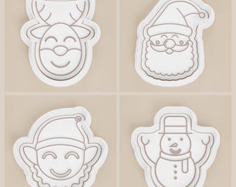 May include: Four white plastic cookie cutters in the shapes of Christmas characters. The shapes include a reindeer, Santa Claus, an elf, and a snowman. Each cutter has a detailed outline of the character's face and features.