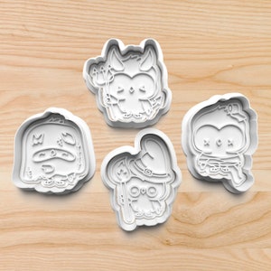 May include: Four white plastic cookie cutters shaped like owls with different Halloween costumes. The owls are wearing a witch hat, a devil costume, a ghost costume, and a mummy costume.