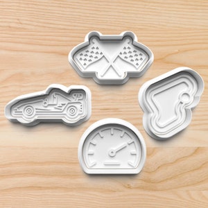 May include: Set of four white plastic cookie cutters shaped like a race car, checkered flags, a racetrack, and a speedometer.