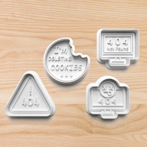May include: Four white plastic cookie cutters shaped like a computer screen, a warning sign, a cookie, and a computer screen with a sad face. The computer screens display the text "404 Not Found" and "404". The warning sign displays the text "! 404". The cookie cutter shaped like a cookie displays the text "I'm deleting cookies".
