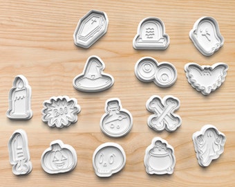 May include: A set of 15 white plastic Halloween cookie cutters. The cutters are shaped like a ghost, a bat, a pumpkin, a witch's hat, a coffin, a skull, a potion bottle, a candle, a tombstone, a pair of eyeballs, a cauldron, a pair of crossed bones, a ghost holding a sign that says "BOO", and a ghost holding a sign that says "BOO".