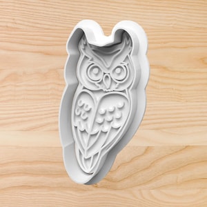 May include: White plastic owl cookie cutter. The owl has large eyes and detailed feathers.
