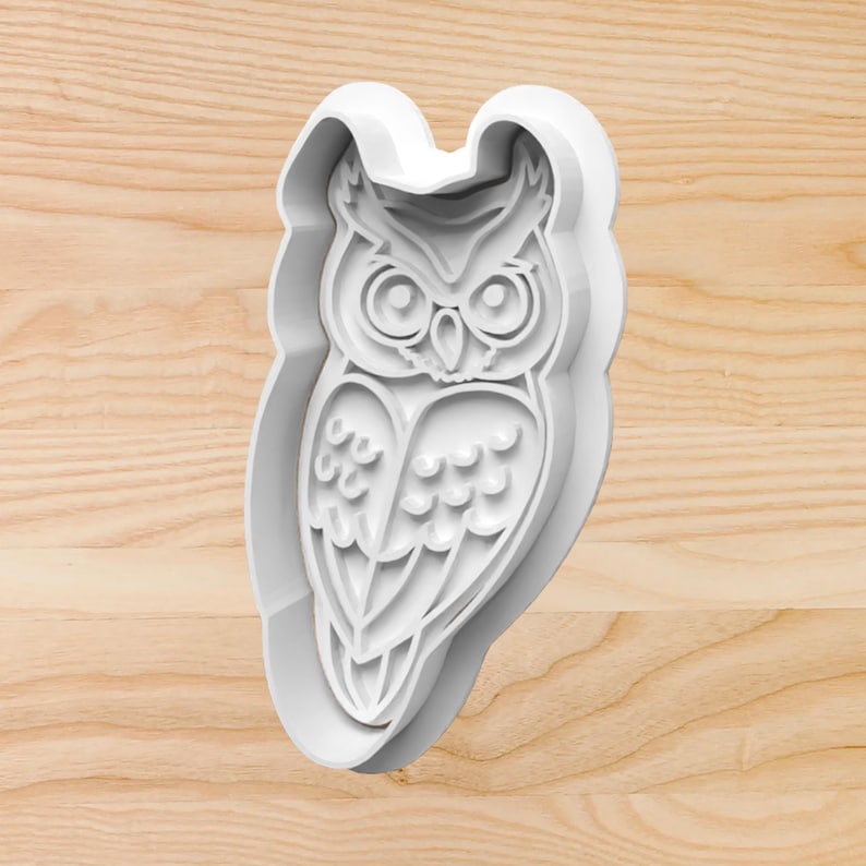 May include: White plastic owl cookie cutter. The owl has large eyes and detailed feathers.