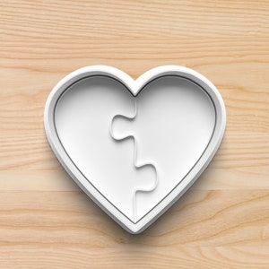Puede incluir: Cortador de galletas de plástico blanco en forma de corazón con un diseño de rompecabezas.