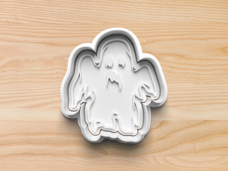 May include: White plastic cookie cutter shaped like a ghost with a toothy grin.