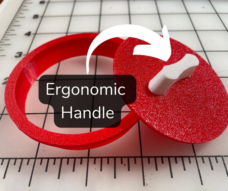 May include: A red plastic cookie cutter with an ergonomic handle. The cutter is in the shape of a heart. The text "Ergonomic Handle" is displayed on the image.