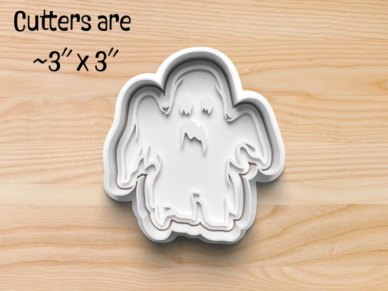May include: White plastic cookie cutter shaped like a ghost with a toothy grin. Cutters are approximately 7.6 cm by 7.6 cm.