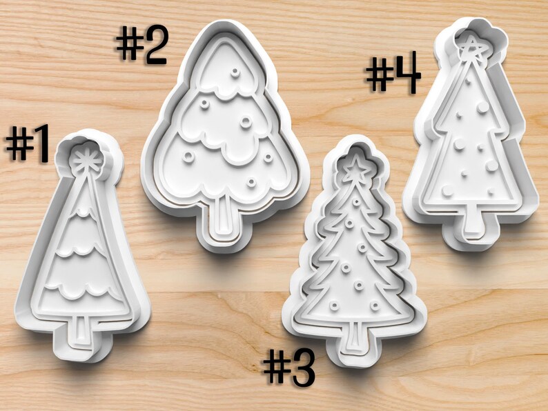 May include: Four white plastic Christmas tree-shaped cookie cutters. Each cutter has a different design, including a star on top. The numbers #1, #2, #3, and #4 are printed above or next to each cutter.