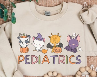 May include: A tan sweatshirt with a Halloween-themed design featuring a panda, cat, giraffe, and bat. The text "PEDIATRICS" is printed in colorful letters below the animals.