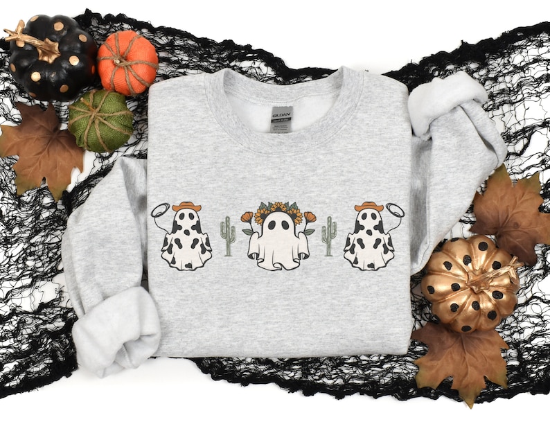 May include: A gray sweatshirt with a design of three ghosts wearing cowboy hats and floral crowns. The ghosts are in front of a cactus.