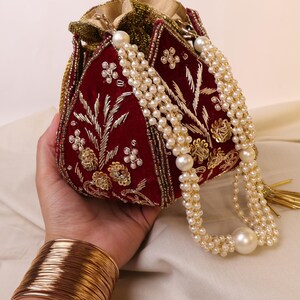 May include: A red velvet drawstring bag with gold embroidery and a pearl and tassel chain.