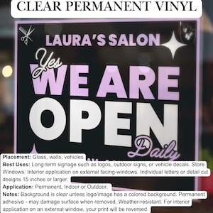 May include: A black and white sign with pink lettering that reads "Yes We Are Open Daily". The sign also includes the text "Laura's Salon" and a small image of scissors. The sign is made of clear permanent vinyl and is suitable for use on glass, walls, or vehicles.