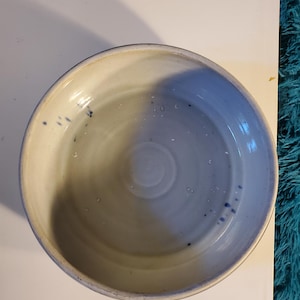 Może przedstawiać: Biała ceramiczna miska z niebieskim rantem i niebieskimi plamkami wewnątrz. Miska jest pusta.