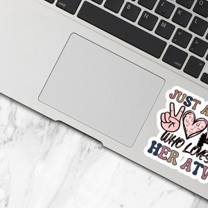 May include: A sticker featuring a peace sign, a heart with a leopard print, and an ATV. The text reads "Just a girl who loves her ATV".