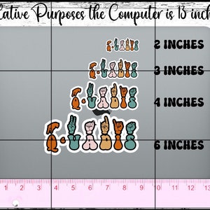May include: A ruler measuring 14 inches is placed below a laptop computer screen. The screen has four rows of colourful hand-drawn stickers with the word "QUADRIS" written in each row. The stickers are arranged in a staggered pattern. The text "2 INCHES", "3 INCHES", "4 INCHES", and "6 INCHES" is written to the right of each row of stickers.
