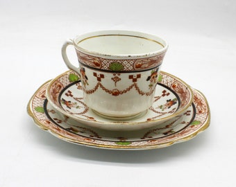 May include: A vintage teacup and saucer set with a delicate floral pattern in shades of brown, red, and green. The set features a scalloped edge and gold trim.