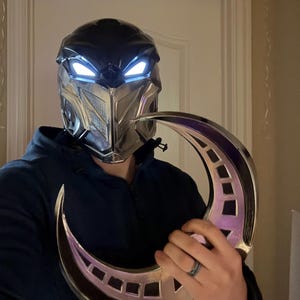 May include: A silver and black helmet with glowing blue eyes and a silver crescent moon prop.