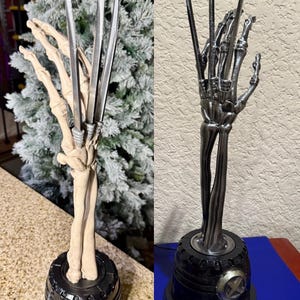 May include: A silver skeletal hand with three claws extended upwards. The hand is attached to a black base with a silver X-Men logo.