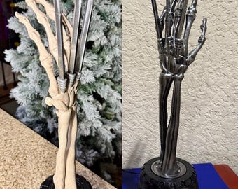 May include: A silver skeletal hand with three claws extended upwards. The hand is attached to a black base with a silver X-Men logo.