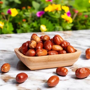 May include: A wooden bowl filled with dried jujubes, a type of fruit, on a marble surface. There are also several jujubes scattered around the bowl.