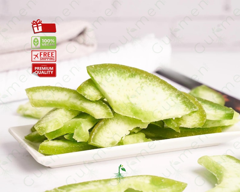 May include: A white ceramic dish filled with green candied citrus peel. The peel is arranged in a pile, with some pieces overlapping.