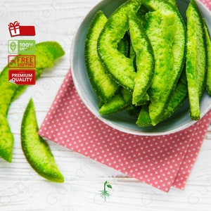 May include: A bowl of green candied citrus fruit slices on a pink and white polka dot napkin. The fruit is arranged in a pile and is glistening.