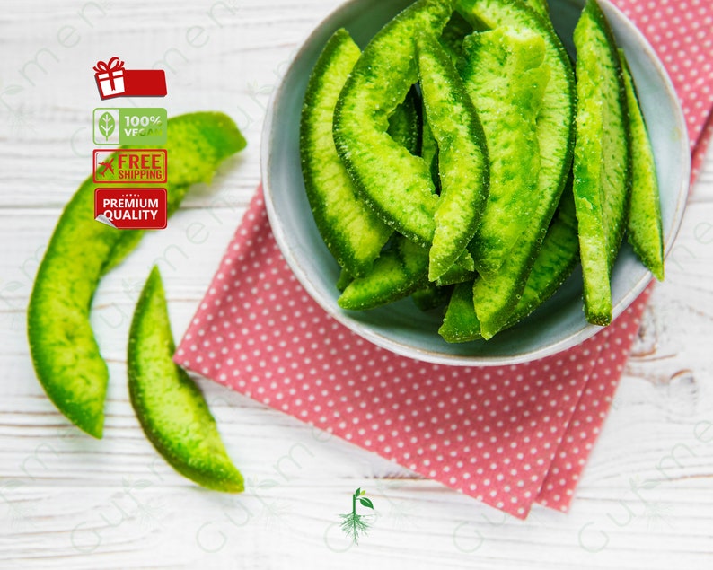 May include: A bowl of green candied citrus fruit slices on a pink and white polka dot napkin. The fruit is arranged in a pile and is glistening.