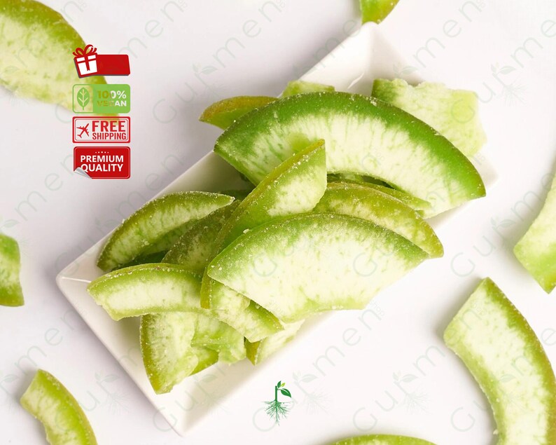 May include: A white ceramic dish filled with green candied citrus fruit slices. The fruit is arranged in a decorative pattern and has a light green color.