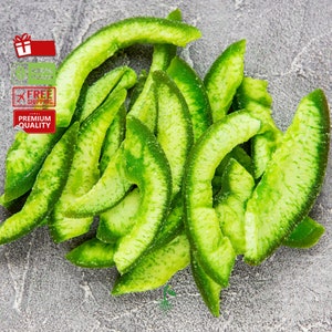 May include: A pile of dried green citrus fruit slices. The slices are arranged in a semi-circle shape, with the tips of the slices pointing towards the center of the circle. The slices are a light green color and have a slightly translucent appearance.