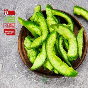 May include: A bowl of green candied citrus peel. The peel is arranged in a pile and is a bright green color. The bowl is made of dark wood and has a natural finish.
