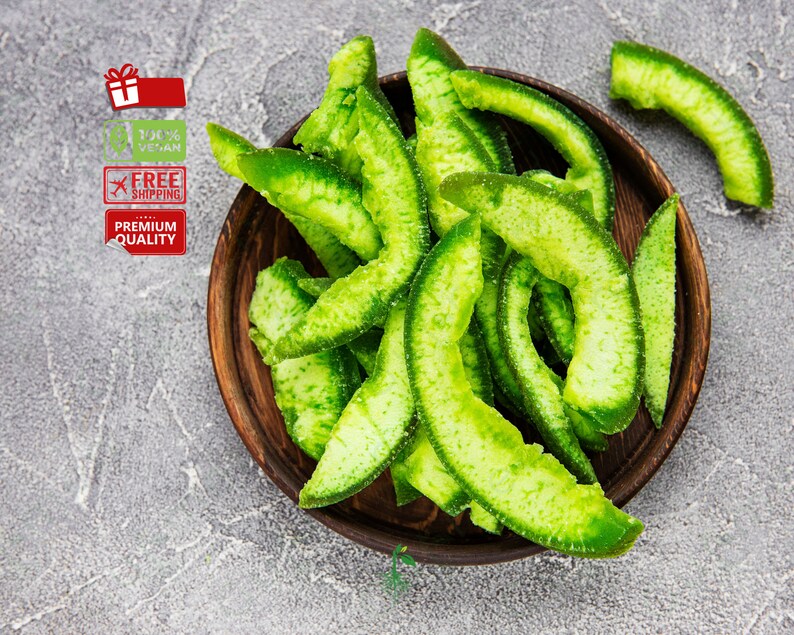 May include: A bowl of green candied citrus peel. The peel is arranged in a pile and is a bright green color. The bowl is made of dark wood and has a natural finish.