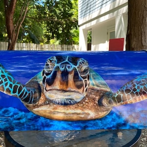 May include: A metal mailbox featuring a vibrant, full-color painting of a sea turtle swimming in deep blue water. The turtle is centered, facing forward with outstretched flippers. The artist's signature, Marza Wagner, is visible in the bottom left corner.