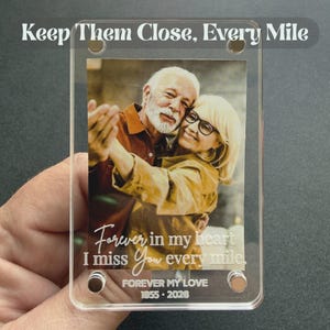 May include: A clear acrylic photo frame with a picture of an elderly couple dancing. The frame has the text "Keep Them Close, Every Mile", "Forever in my heart I miss You every mile", and "FOREVER MY LOVE 1955-2026".