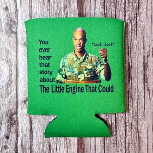 Könnte beinhalten: Grüner Getränkehalter mit dem Text "You ever hear that story about The Little Engine That Could" und einem Bild eines Mannes in einem Tarnhemd. Der Satz "*toot toot*" ist ebenfalls enthalten.