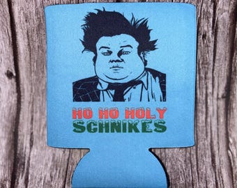 May include: A light blue foam beverage insulator featuring a black graphic illustration of a man with messy hair wearing a suit and tie. Below the illustration, the text reads HO HO HOLY SCHNIKES in red and green block lettering.
