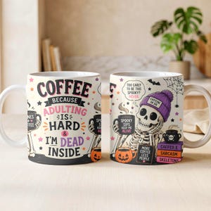 May include: Two white ceramic mugs featuring Halloween-themed graphics. One mug displays the text "COFFEE BECAUSE ADULTING IS HARD & I'M DEAD INSIDE". The other shows a skeleton wearing a purple beanie with "CAFFEINE OR DIE" text and books.