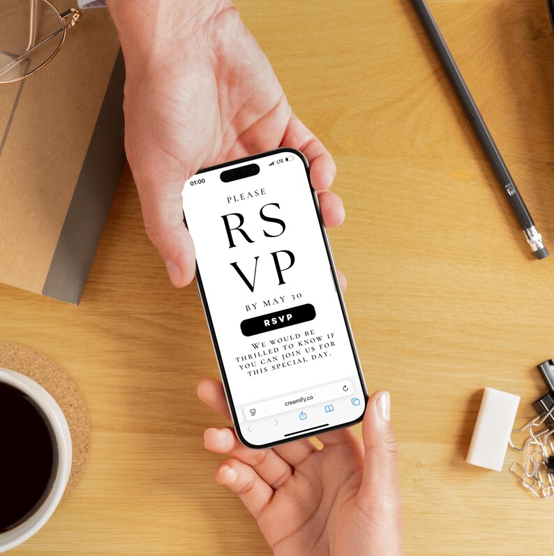 Op de afbeelding: Een smartphone toont een digitale RSVP-uitnodiging met de tekst "PLEASE RSVP BY MAY 30". De telefoon wordt door twee handen vastgehouden, met een houten bureau en kantoorbenodigdheden op de achtergrond.