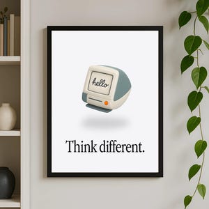 May include: A black framed poster with a white background. The poster features a cartoon image of a vintage computer with the word "hello" on the screen. The text "Think different." is printed below the image.